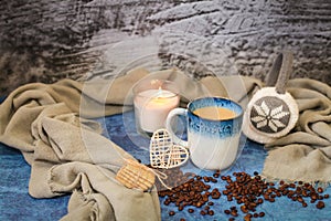 Autumn and winter background with candle, scarf, mug of cocoa, coffee or hot chocolate with scattered coffee beans