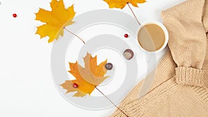 Autumn or winter composition. A cup of coffee, a gift, dry autumn leaves, a beige sweater on a white background. Flat lay, top