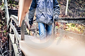 Autumn, winter, or fall walk in forest. Man on a wooden trail, path or bridge. Happy hiker with jacket and jeans enjoying outdoor.