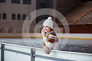 Autumn, Winter portrait: Young smiling woman dressed in a warm woolen cardigan, gloves and hat posing outside.