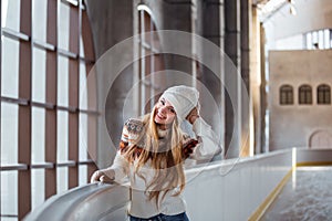 Autumn, Winter portrait: Young smiling woman dressed in a warm woolen cardigan, gloves and hat posing outside.