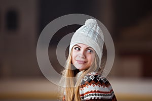 Autumn, Winter portrait: Young smiling woman dressed in a warm woolen cardigan, gloves and hat posing outside.