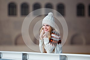 Autumn, Winter portrait: Young smiling woman dressed in a warm woolen cardigan, gloves and hat posing outside.