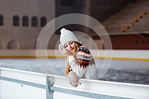 Autumn, Winter portrait: Young smiling woman dressed in a warm woolen cardigan, gloves and hat posing outside.