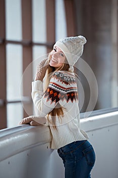 Autumn, Winter portrait: Young smiling woman dressed in a warm woolen cardigan, gloves and hat posing outside.