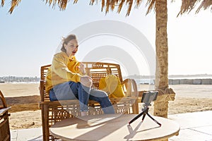 Autumn winter season in tropical seaside resort. Middle-aged woman recording video on smartphone