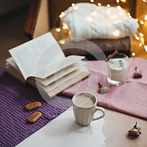 Autumn or winter still life. Coffee cup, candle, flowers, book and knitted sweaters. Hygge lifestyle, cozy autumn mood. Flat lay