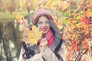 Autumn woman with bright maple leaf outdoors