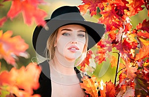 Autumn woman in hat near colorful autumn leaves. Pretty romantic tenderness autumn model.