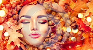 Autumn woman makeup. Beautiful autumn model girl portrait with bright yellow, red and orange color leaves and oak acorns