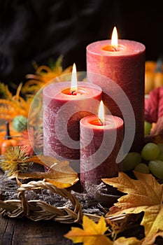 Autumnal arrangement with three lit candles and fall leaves