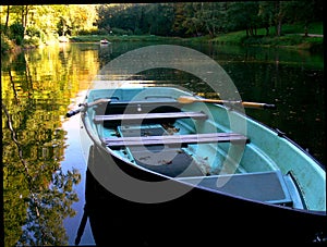 Lake with blue rowing boat and yellow reflection in the water