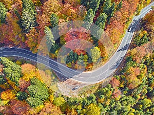 Autumnal landscape view of a mountain road and some cars passing by