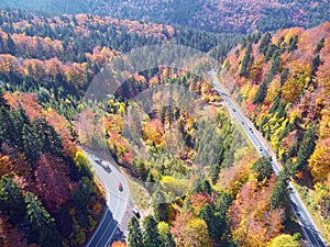 Autumnal landscape view of a mountain road and some cars passing by