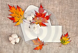 Autumnal maple leaves, cotton flowers in postal envelope and blank white sheet with space for text on background coarse cloth