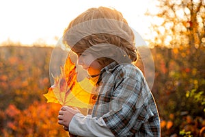 Autumnal mood. Happy child laughing and playing leaves in autumn outdoors.