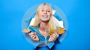 Autumnal mood. Smiling woman with maple leaves looking through paper hole. Discount. Season sales. Advertising.