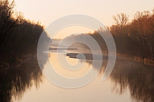 Autumnal morning mist river idyll by sunrise, brownish-orange shades