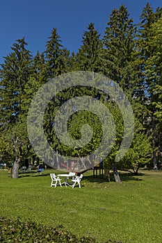 Autumnal view toward public garden with picnic table at chair lawn, tree and open-air kindergarten, Cortina d`Ampezzo, Dolomite