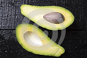 Avacado and seed on black wooden table, top view