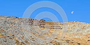 Lavínová ochrana alebo bariéra na horskom priechode Lomnické sedlo vo Vysokých Tatrách s mesiacom na modrej oblohe.