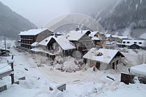 avalanche of snow sweeps over mountain village, burying buildings and roads
