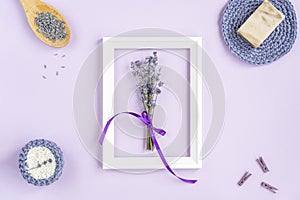 avender flowers in a frame on a purple background. cosmetic set with lavender herbs, handmade soap bars and sea salt.