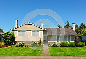 Average family house with green lawn and trees in front on blue sky background