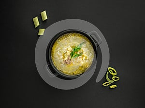 Avgolemono, traditional greek chicken soup with egg on black background