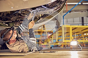 Aviation mechanic is checking big jet before departure photo
