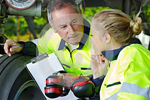 Aviation mechanic with female apprentice by aircraft landing gear