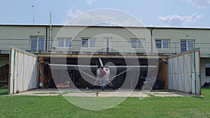 Aviator fixing airplane propeller inside repair hangar on countryside aerodrome.