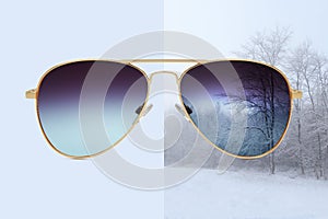 Aviator sunglasses isolated on blue and winter background with snow covered trees, concept of polarized protective lenses