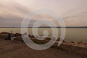 Avid fisherman fishing spot. Fishing tackle on a pier on the background of the lake Balaton. Vibrant sky in cloudy day.