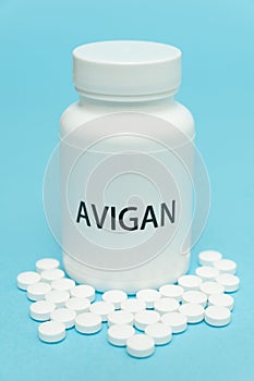 AVIGAN Favipiravir in white bottle packaging with scattered pills. Treatments for COVID-19. isolated on blue background