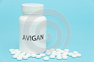 AVIGAN Favipiravir in white bottle packaging with scattered pills. Treatments for COVID-19. Isolated isolated on blue background