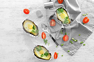 Avocado baked with eggs in foil on wooden table