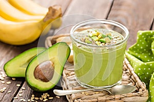 Avocado and banana smoothie with oats with ingredients in glass jar on wooden background
