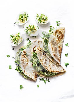 Avocado cream cheese micro greens quesadilla and boiled eggs on a light background, top view. Delicious healthy breakfast, snack,