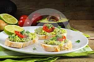 avocado cream or guacamole on baguette sandwiches freshly prepared with ingredients like lemon and tomatoes on a rustic wooden