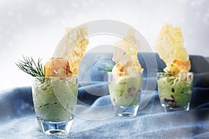 avocado cream guacamole with tiger prawn shrimps and crisp cheese cracker in three glasses, festive appetizer or party snack on
