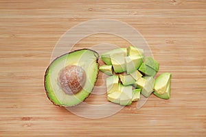 Avocado cut half and chopped on wooden board background