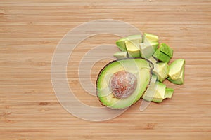 Avocado cut half and chopped on wooden board background with copy space