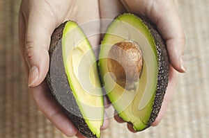 Avocado cut in half with seed in hand