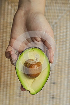 Avocado cut in half with seed in hand