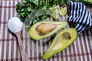 Avocado cut in halves accompanied by salt and lemon.