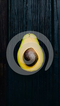 Avocado displayed on dark wooden background, creating striking contrast