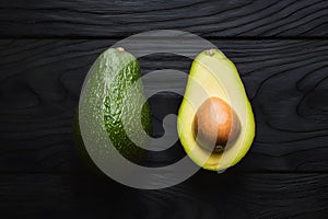 Avocado displayed on dark wooden background, creating striking contrast