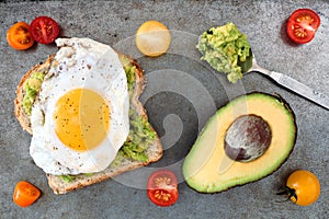 Avocado, egg toast with tomatoes on rustic baking tray