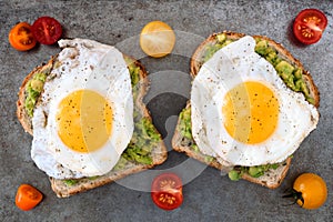 Avocado, egg toast with tomatoes on rustic baking tray